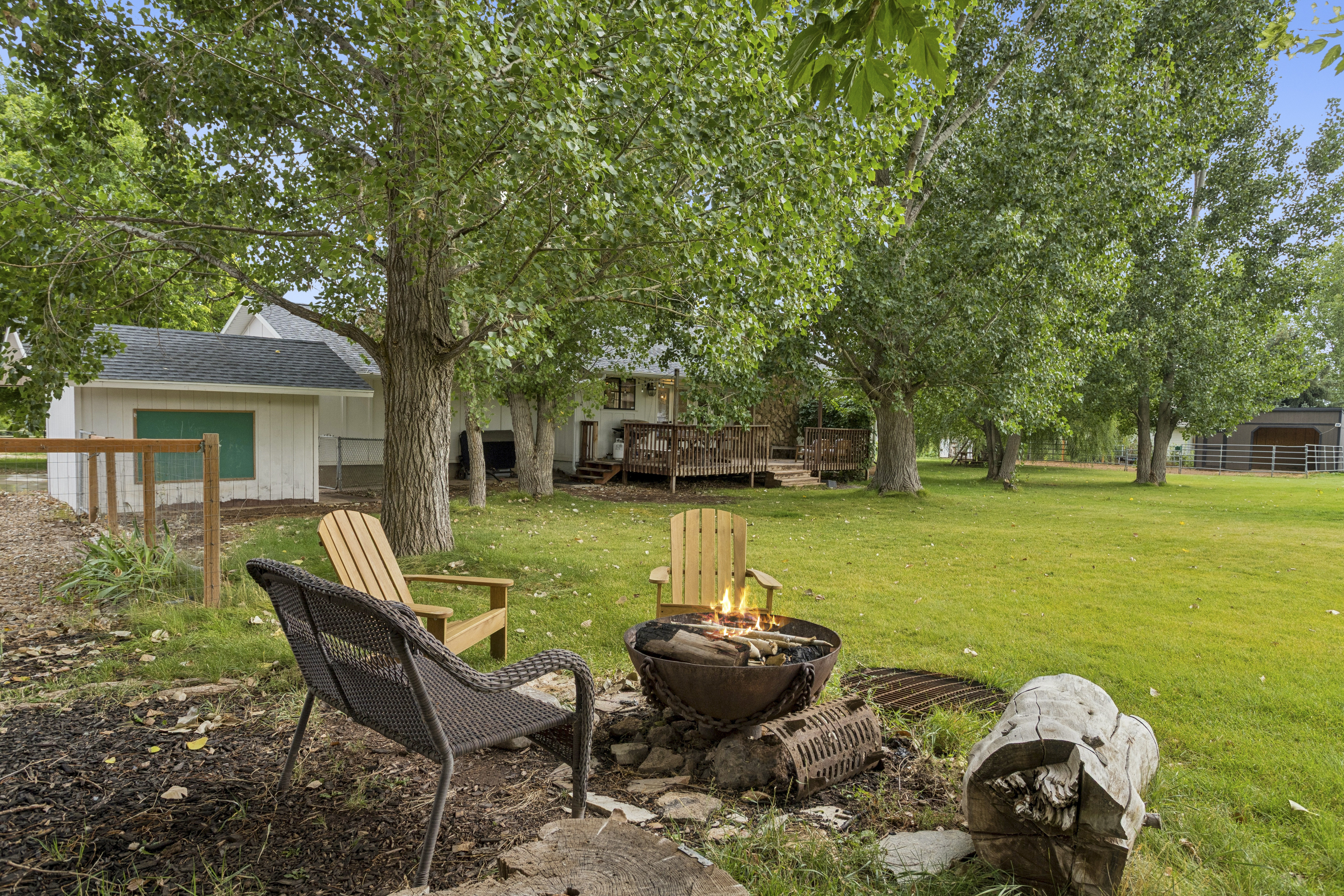 Evening fire pit with Adirondack chairs and outbuildings beyond